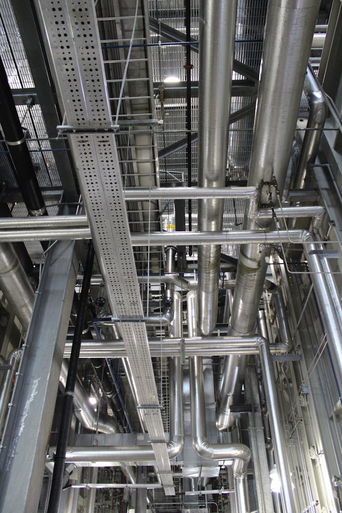 about-us-01 Vertical shot of steel pipes and ventilation in an industrial setting.