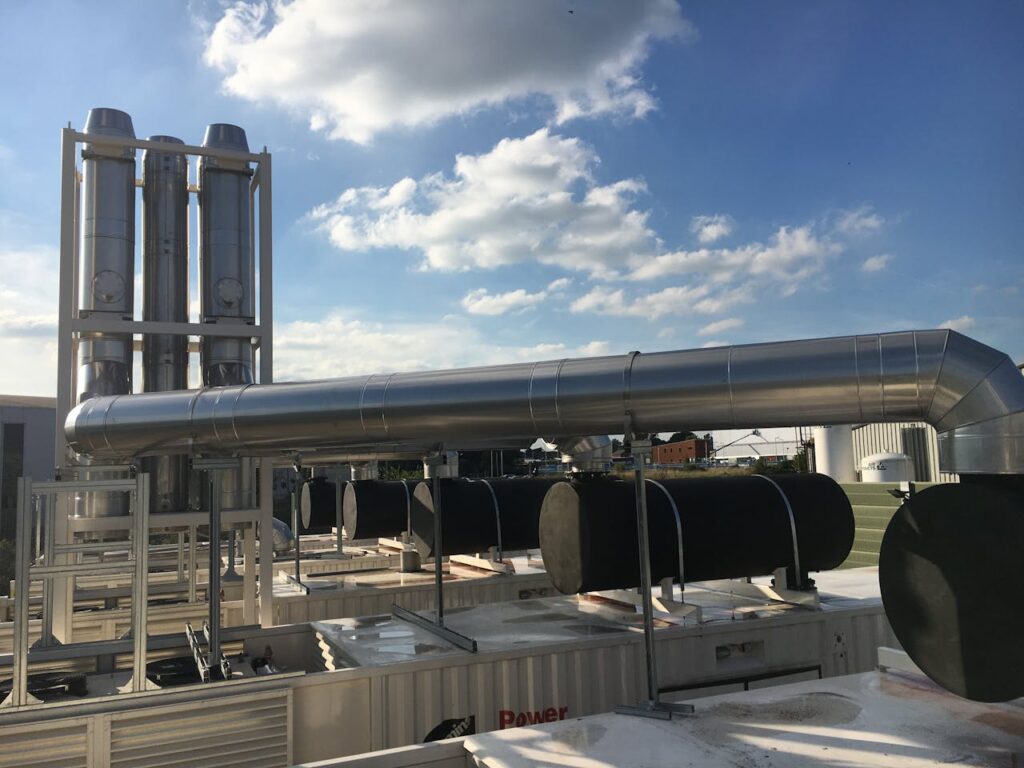 Modern industrial chimneys and support mast with flues against a clear blue sky, showcasing advanced infrastructure.
